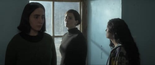 A sparse apartment entryway. At left a teenage girl looking on. To the right her younger sister, looking back at their mother, who eyes the first girl.