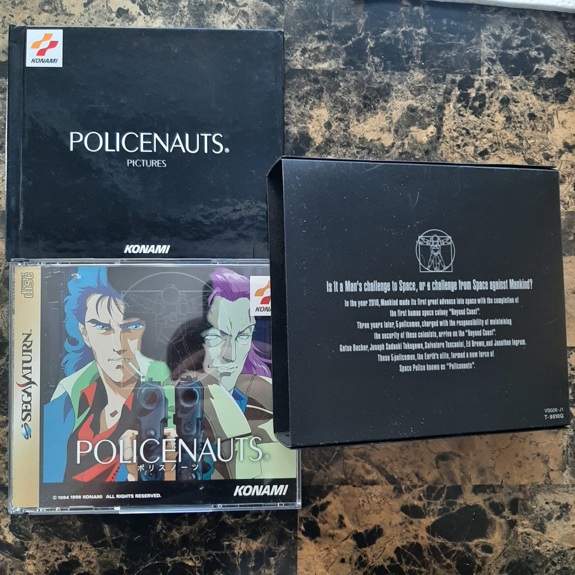 The back of the Policenauts slipcase, with the subtitle "Is it a Man's challenge to Space, or a challenge from Space against Mankind?" A black hardcover book with the title Policenauts Pictures, and the jewel case and manual for the Sega Saturn version of Policenauts.